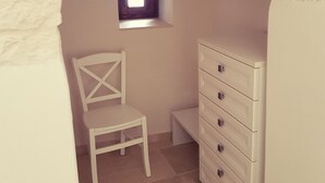 A small room with a white chair, a wooden dresser, and a window with a view. - Lunalì (Alberobello)