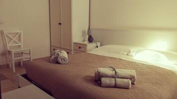A hotel room with a bed, a chair, a wardrobe, and a nightstand with a lamp.