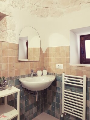 A bathroom with a white sink, a mirror, a towel rack, and a window.