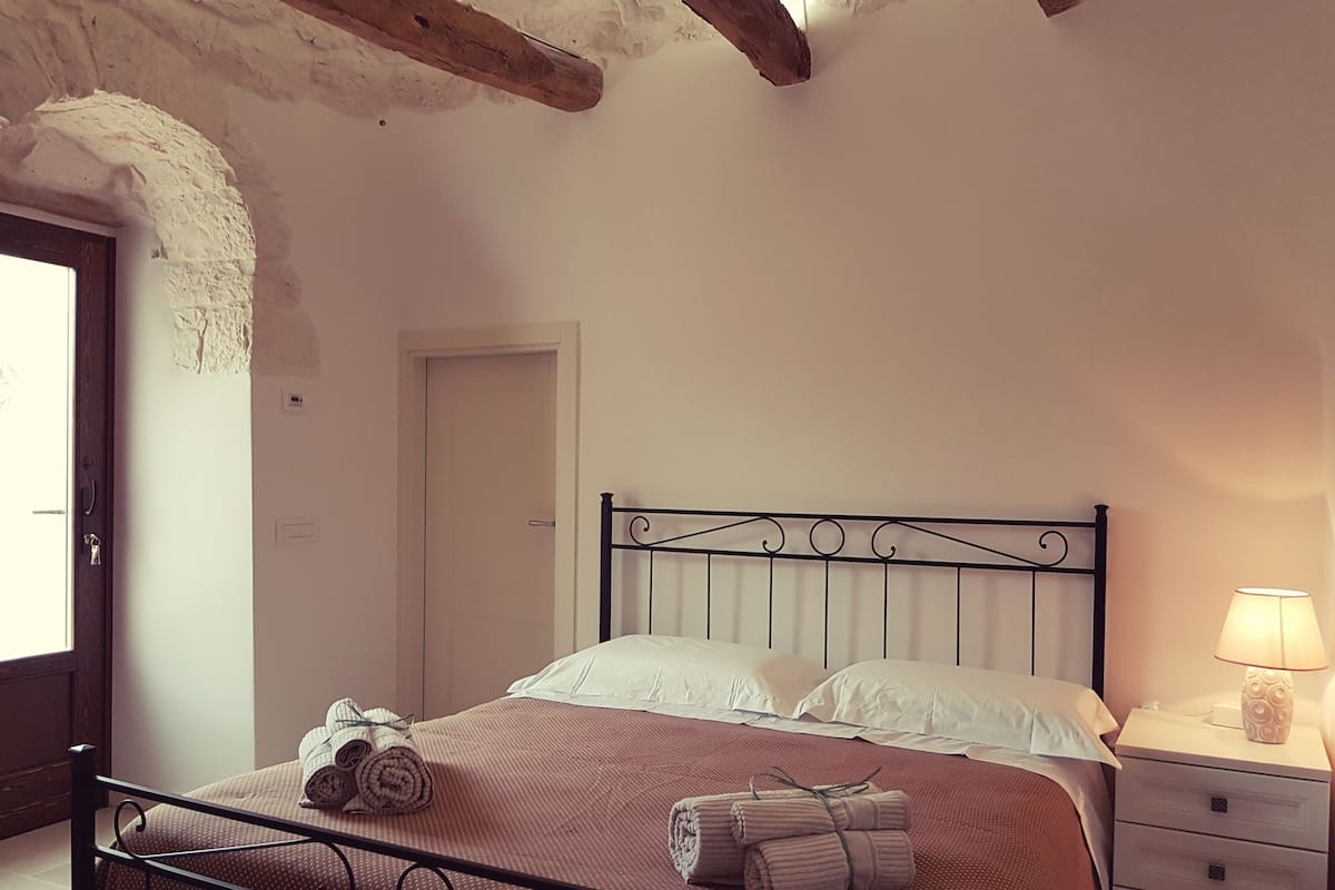 A bedroom with a bed, a nightstand, and a lamp.
