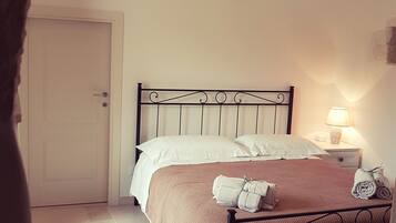 Un dormitorio con cama, mesita de noche, lámpara y puerta.
