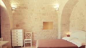 A bedroom with a bed, a dresser, a chair, and a small table. - Lunalì (Alberobello)