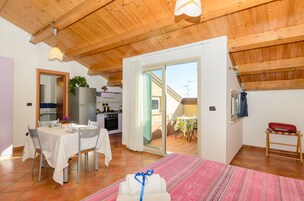 Cocina compacta con refrigerador, estufa y comedor con sillas y mesa.