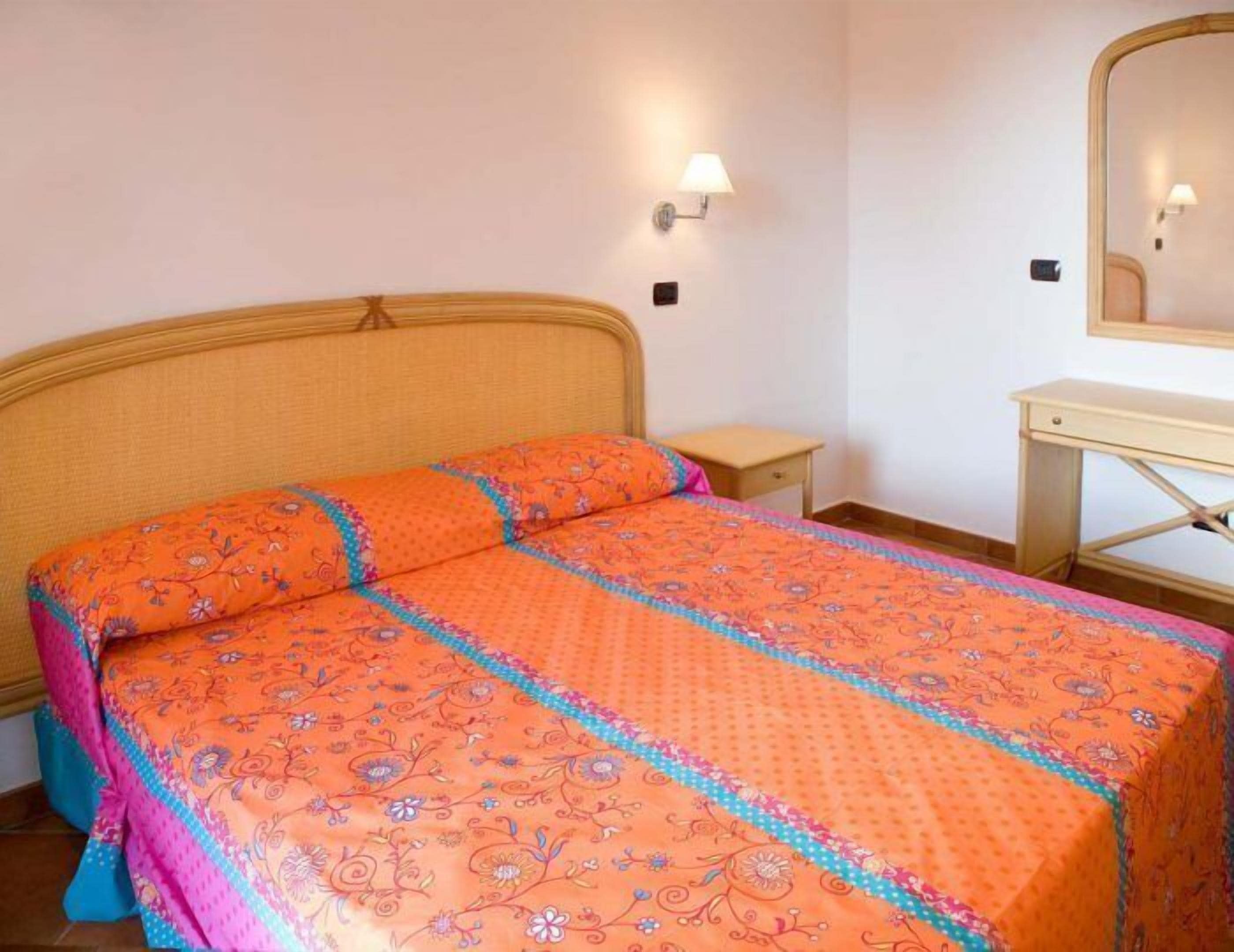 Une chambre à coucher avec un lit, une table de chevet, une commode et un miroir.