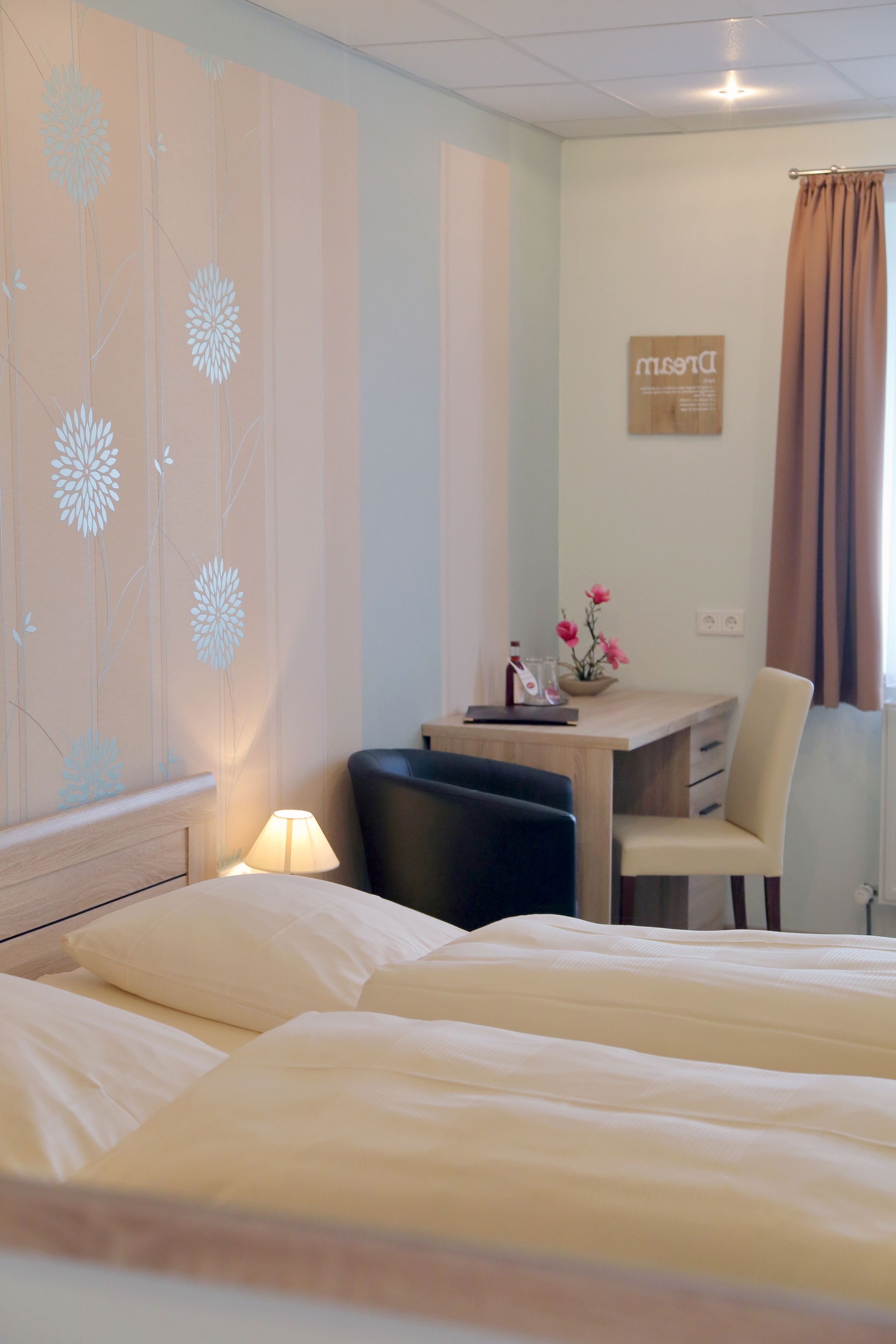 Une chambre d’hôtel comprenant un lit, un bureau avec une chaise, une lampe et un panneau décoratif mural.