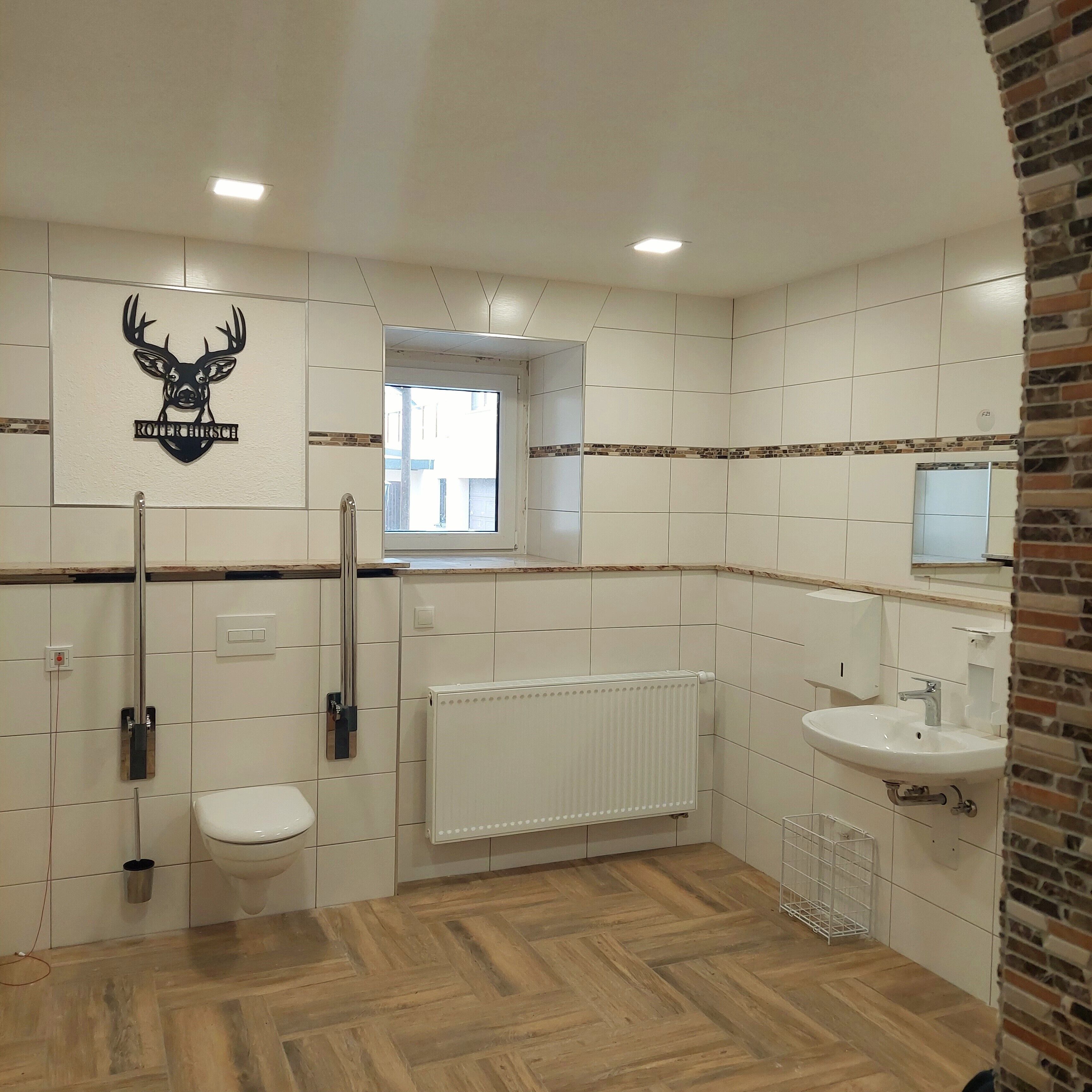 Ein Badezimmer mit Toilette, Waschbecken, Heizkörper und Fenster.