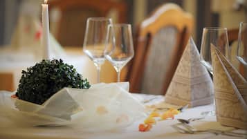 Una mesa lista para una comida, con una vela, copas de vino y un centro de mesa decorativo.