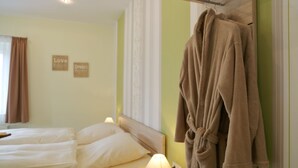 A hotel room with a bed, a robe hanging on the wall, and two motivational wall decorations. - Pension Gasthof und Hotel Roter Hirsch (Claussnitz)