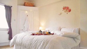 A bedroom with a large bed, a white door, and a window with curtains. - Peel House (Gosport)