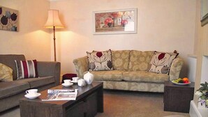 A living room with a sofa, a coffee table, and a side table with a fruit bowl. - Peel House (Gosport)