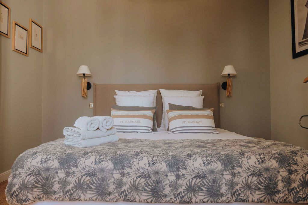 A neatly made bed with a floral-patterned bedspread and two pillows labeled "St. Raphael".