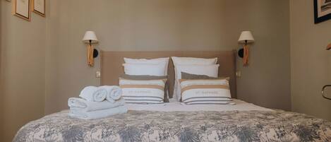 A neatly made bed with a floral-patterned bedspread and two pillows labeled "St. Raphael".