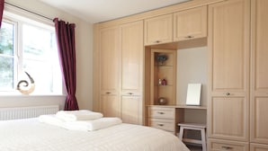 Une chambre à coucher avec un grand lit, une armoire en bois et une petite table de chevet.