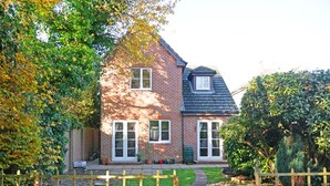 Une maison à deux étages, avec une façade en briques et un toit foncé.