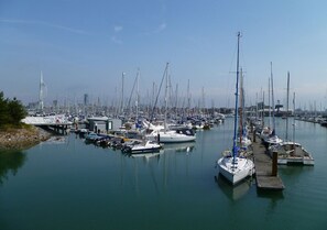 A marina with numerous boats docked at wooden piers, a clear sky, and a distant building. - Harbour View 2 (Gosport)