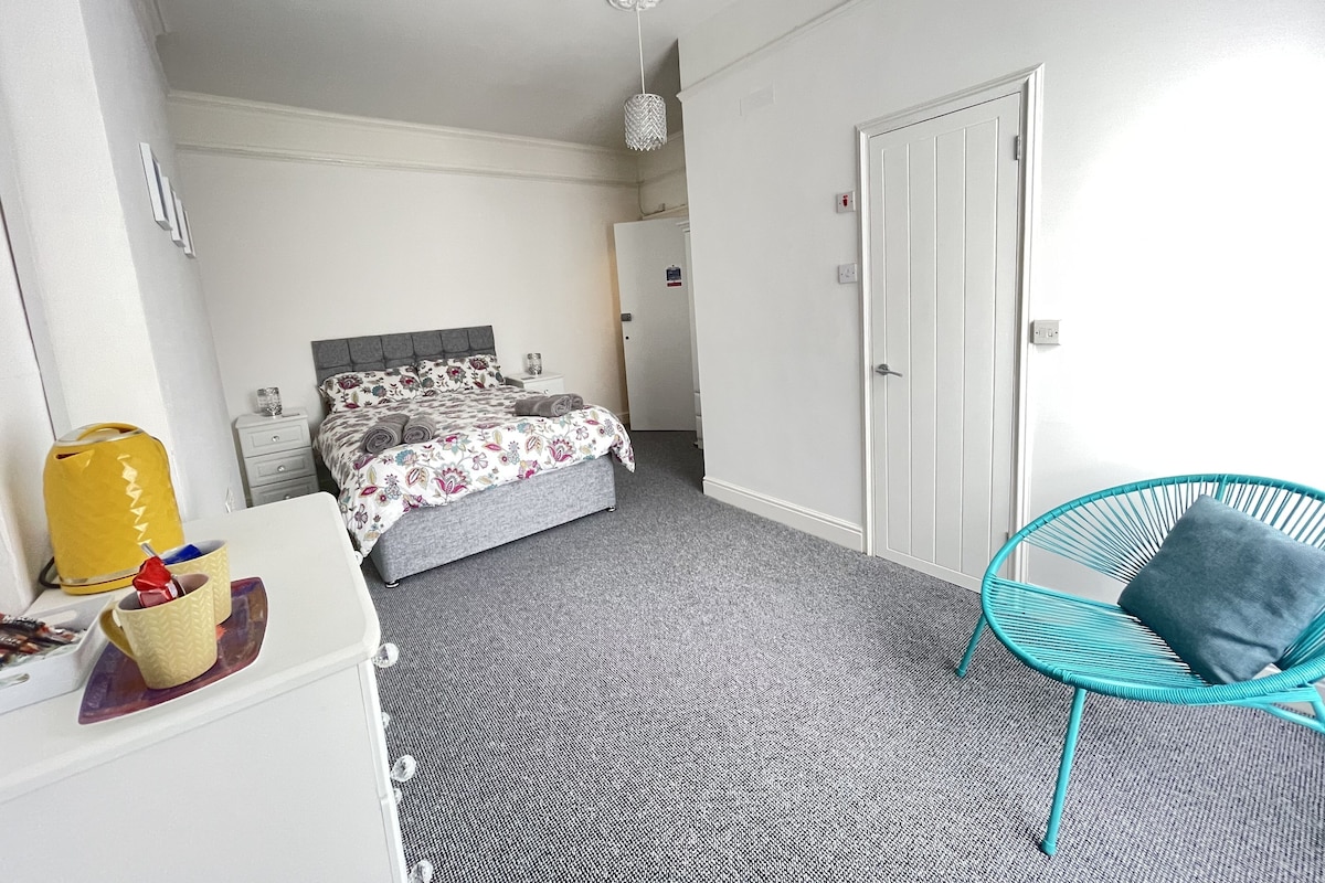 A bedroom with a bed, a chair, and a dresser.