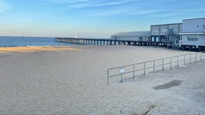 A beach with a pier extending into the water, a lifeguard tower, and a sandy shoreline. - Bon-ami (Lowestoft)