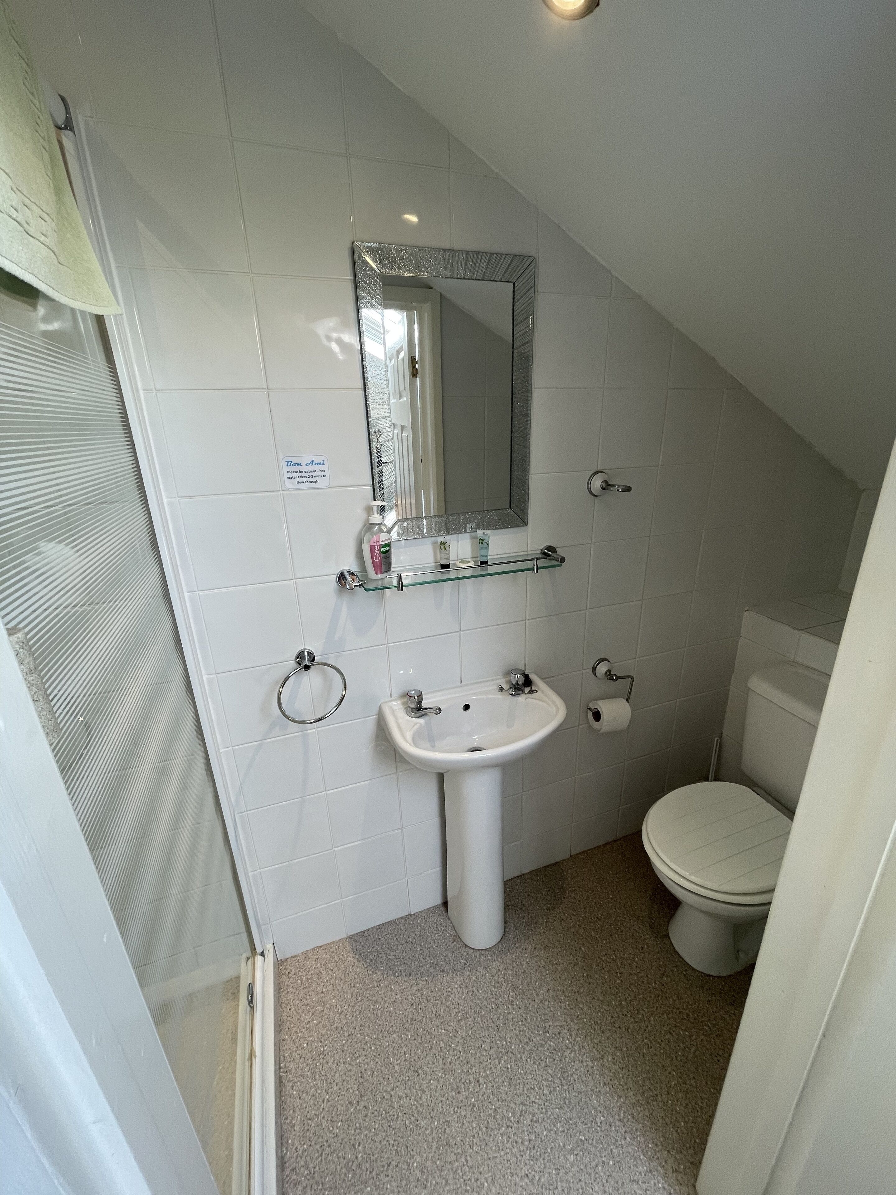 A small, white bathroom with a sink, mirror, and toilet.