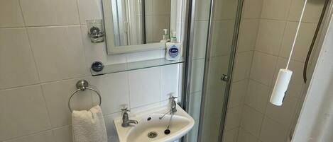 A small bathroom with a toilet, sink, and shower.