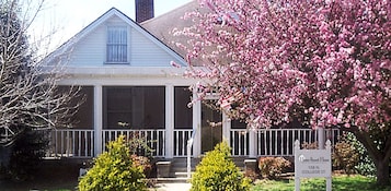 Una casa de dos pisos con un porche, un cartel que dice 'Home Sweet Home Bed & Breakfast' en 108 N. College St., París, TN 38242, y datos de contacto.