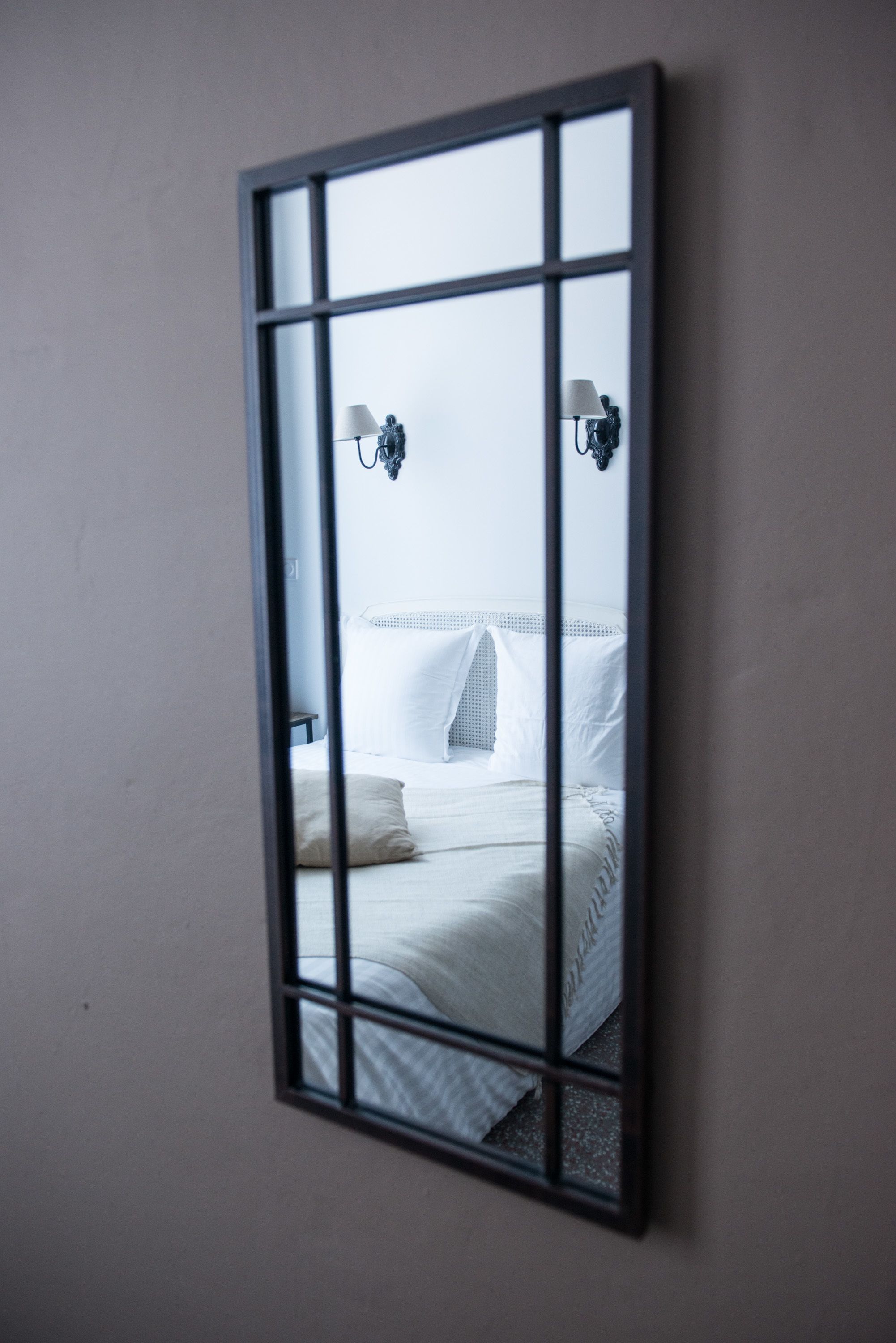 A bedroom with a bed, two wall-mounted lamps, and a window.