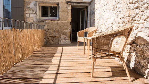 Een houten terras met wicker meubilair en een stenen muur.