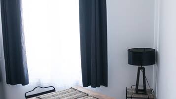 Et lille rum med et bord, stole, en lampe og et vindue med gardiner.