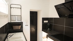 Een moderne keuken met een zwart aanrecht, een witte gootsteen en een zwart fornuis.