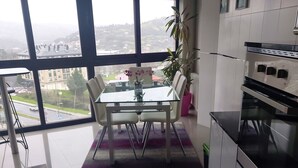 Une cuisine moderne avec un coin repas, de grandes fenêtres et une vue sur la ville.