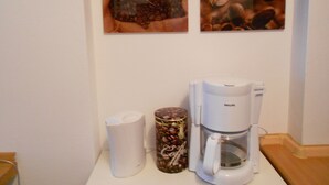 A coffee maker, a white mug, and a coffee bean container on a counter. - Hofgarten (Regensburg)