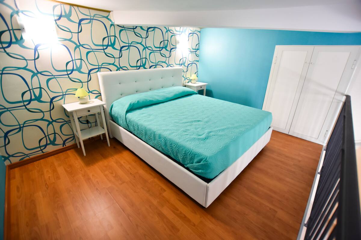 A bedroom with a bed, nightstand, and wardrobe.