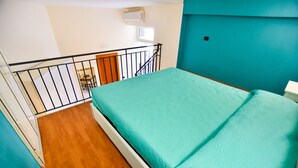 A room with a bed, wooden flooring, a teal wall, a window, and a black railing. - B&B Mary Flower (Naples)