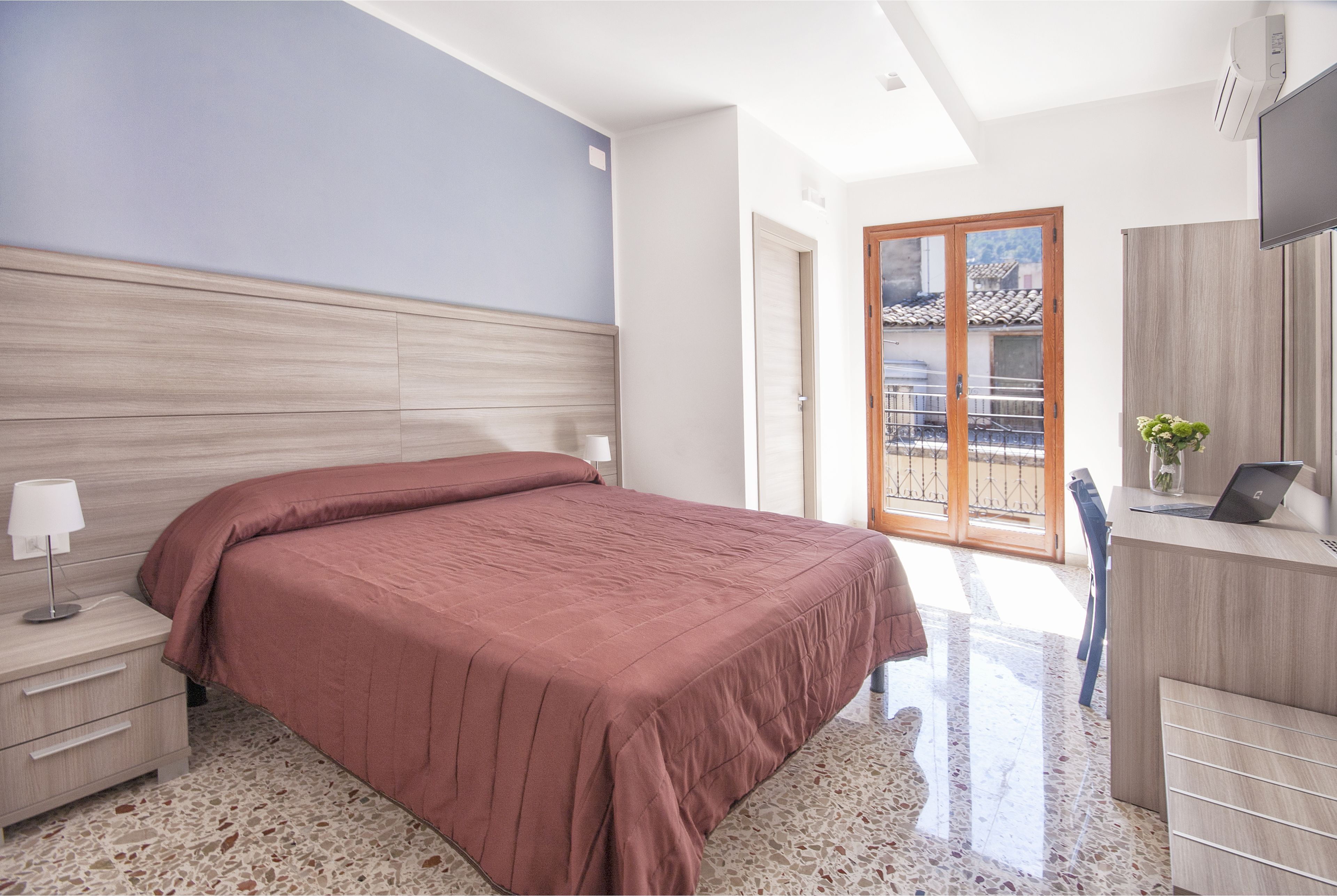 A bedroom with a bed, bedside table, and a desk with a chair.