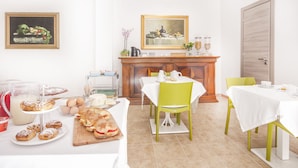 Un coin repas avec un buffet en bois, des nappes blanches et des chaises vertes.