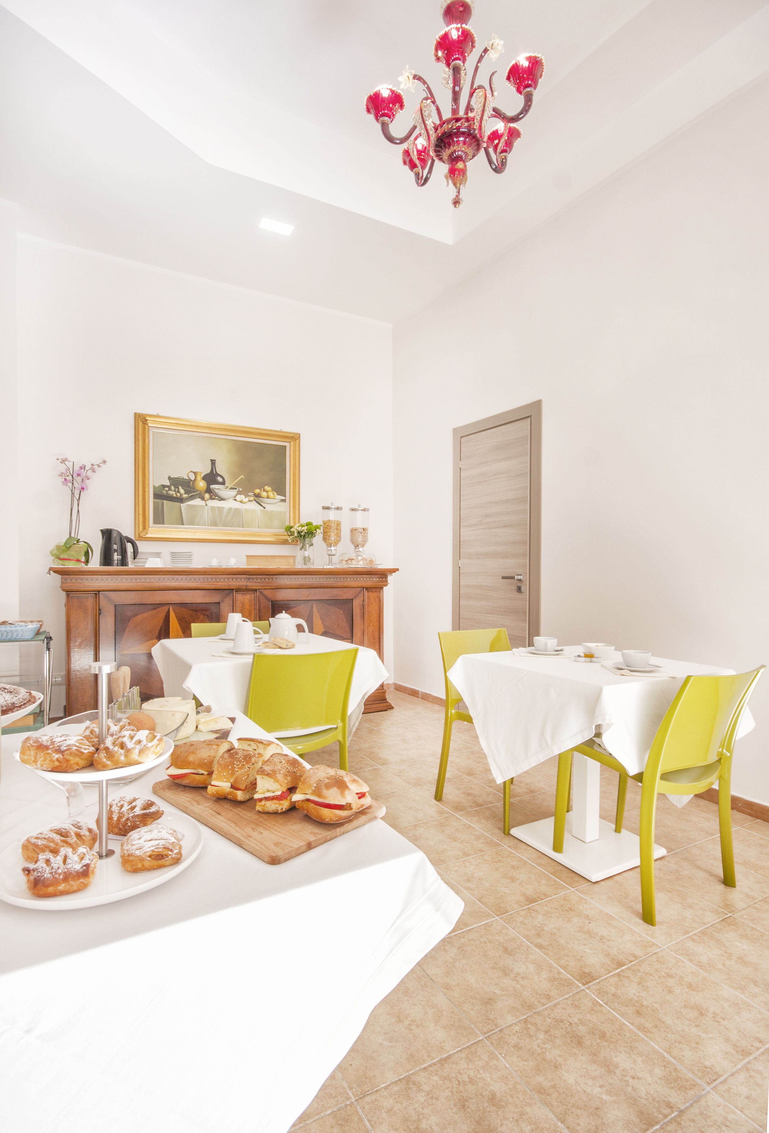 Un comedor con una mesa dispuesta para dos personas, un aparador de madera y una araña.