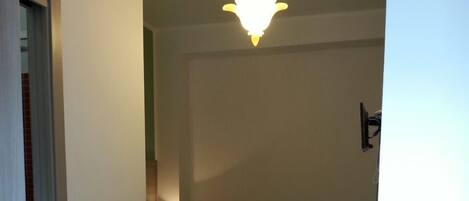 A room with a stone floor, a bed, a desk, and a hanging light fixture.
