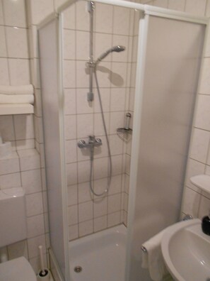 A bathroom with a shower enclosure, a toilet, and a sink. - Beethoven (Regensburg)