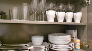 A kitchen shelf with stacked white plates, bowls, and a can of salt.