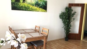 A dining area with a wooden table and chairs, a large potted plant, and a framed picture on the wall. - Newstyle (Regensburg)