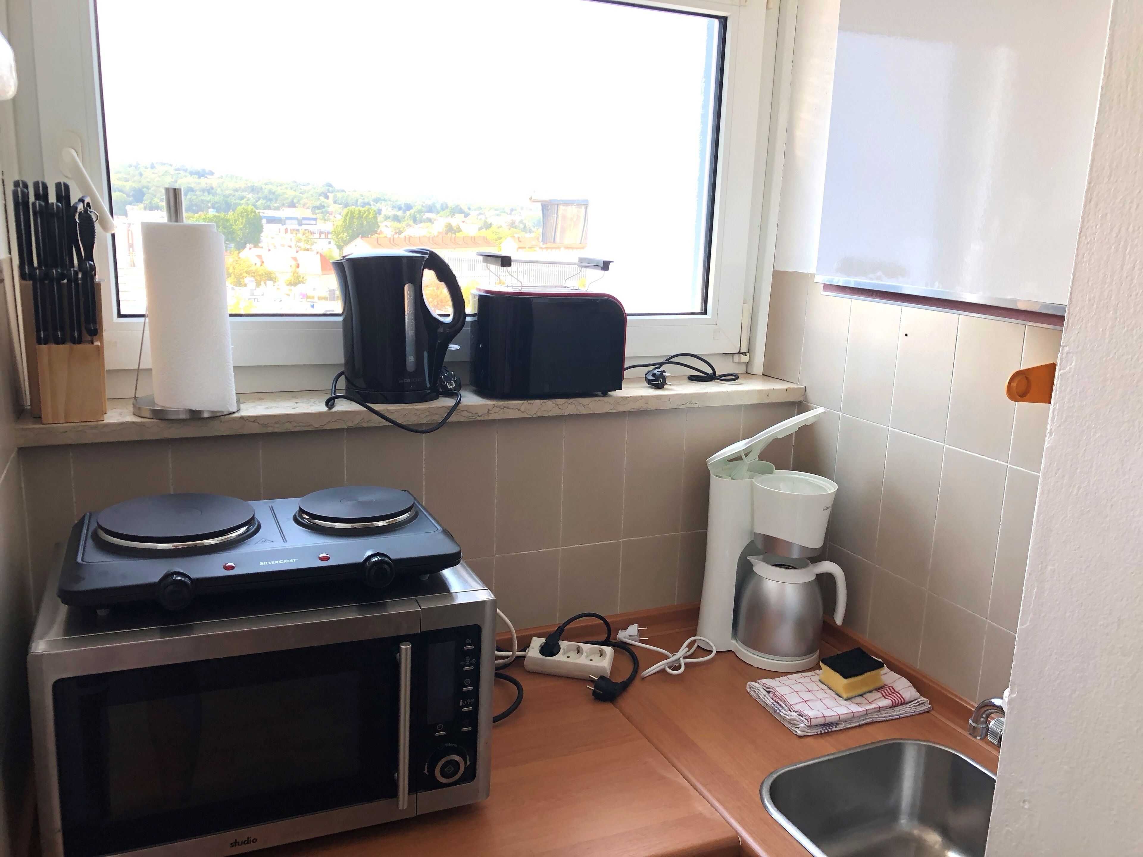 Una cocina con microondas, cafetera y hervidor sobre la encimera.