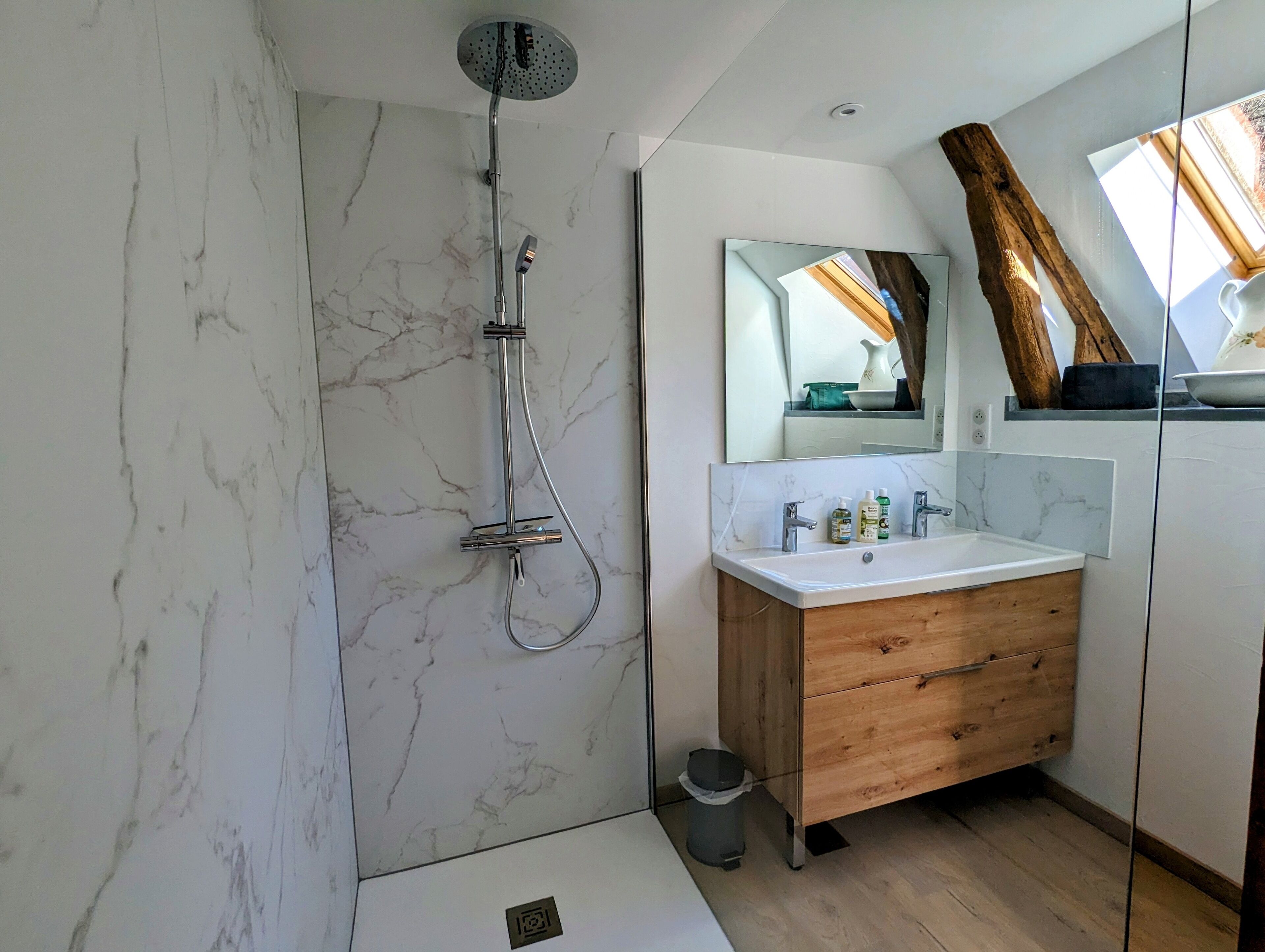 Une salle de bain moderne avec une douche en marbre, un meuble-lavabo en bois et un grand miroir.