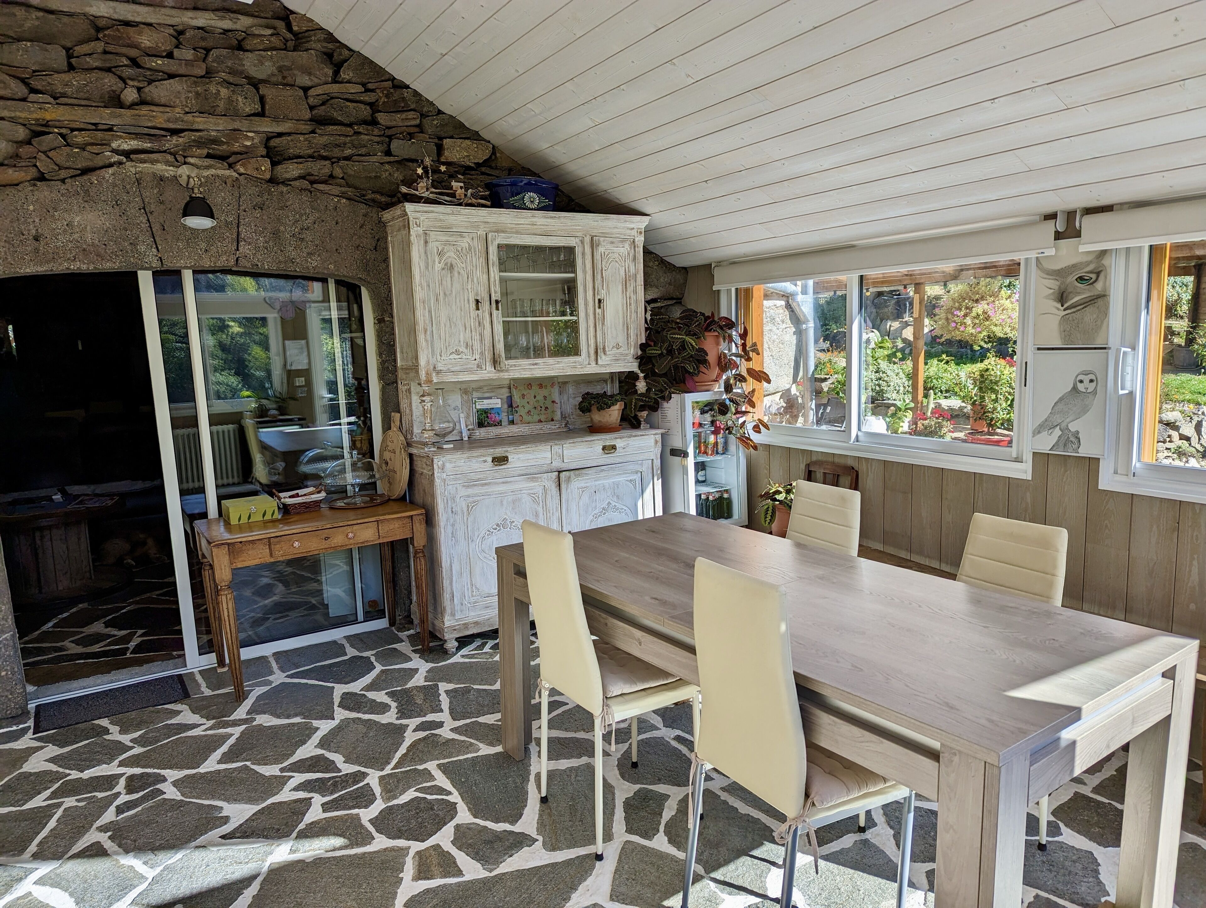 A rustic kitchen with stone walls, wooden cabinets, and a dining area with a table and chairs.