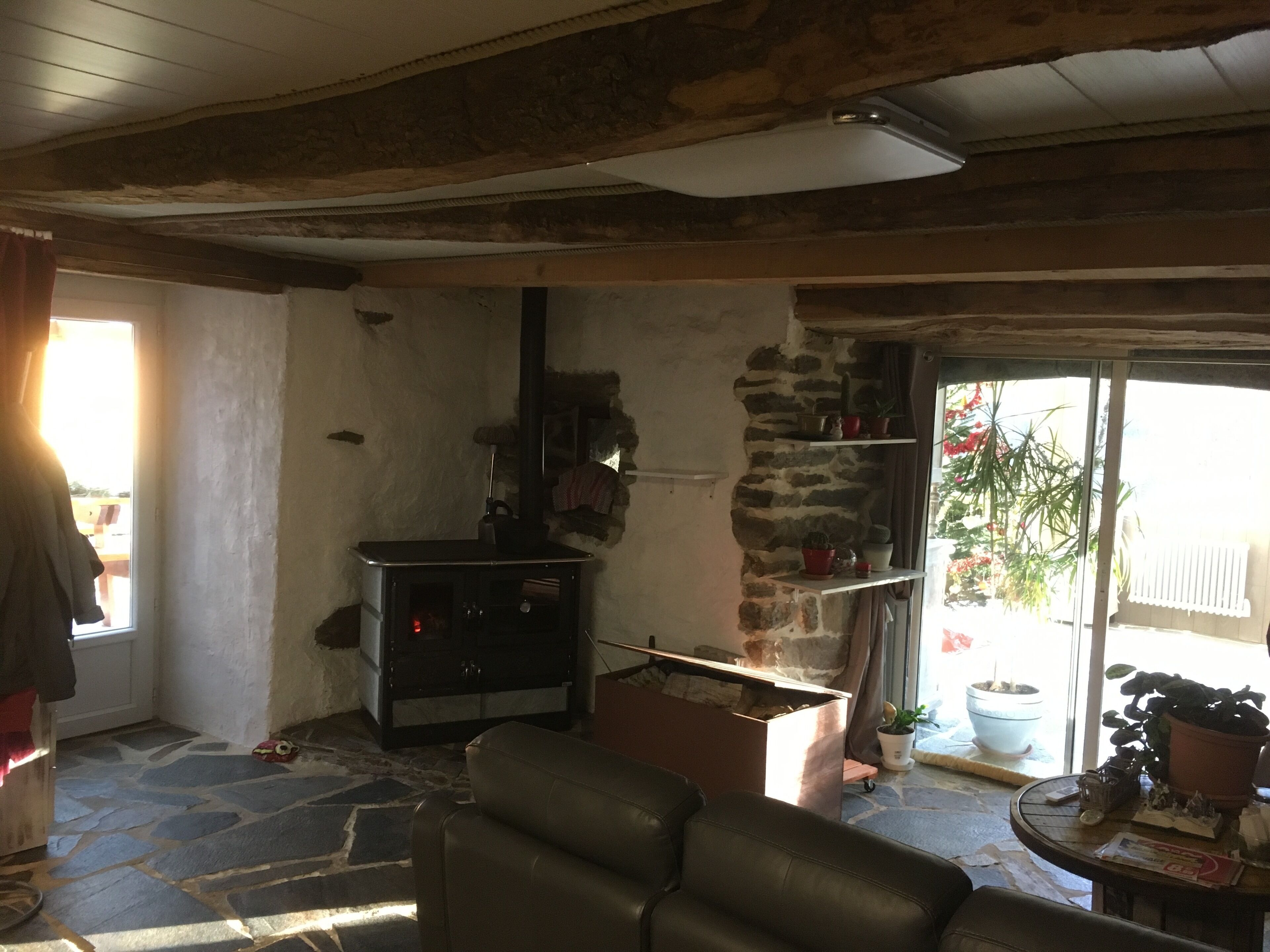 Un interior rústico con chimenea de piedra, un sofá de cuero y una pequeña mesa con adornos.