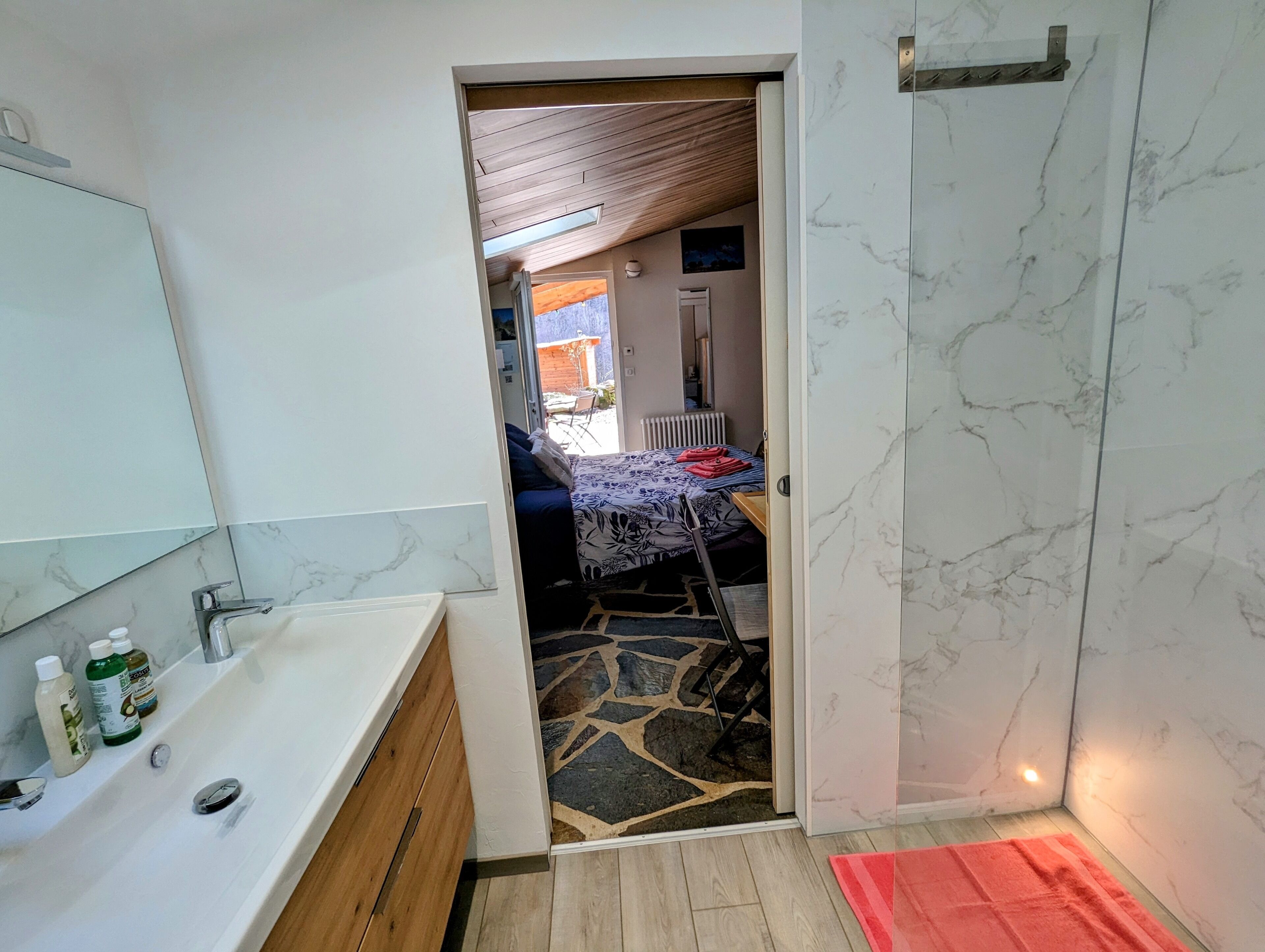 A bathroom with a white sink, mirror, and marble walls.