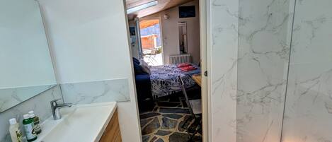 A bathroom with a white sink, mirror, and marble walls.