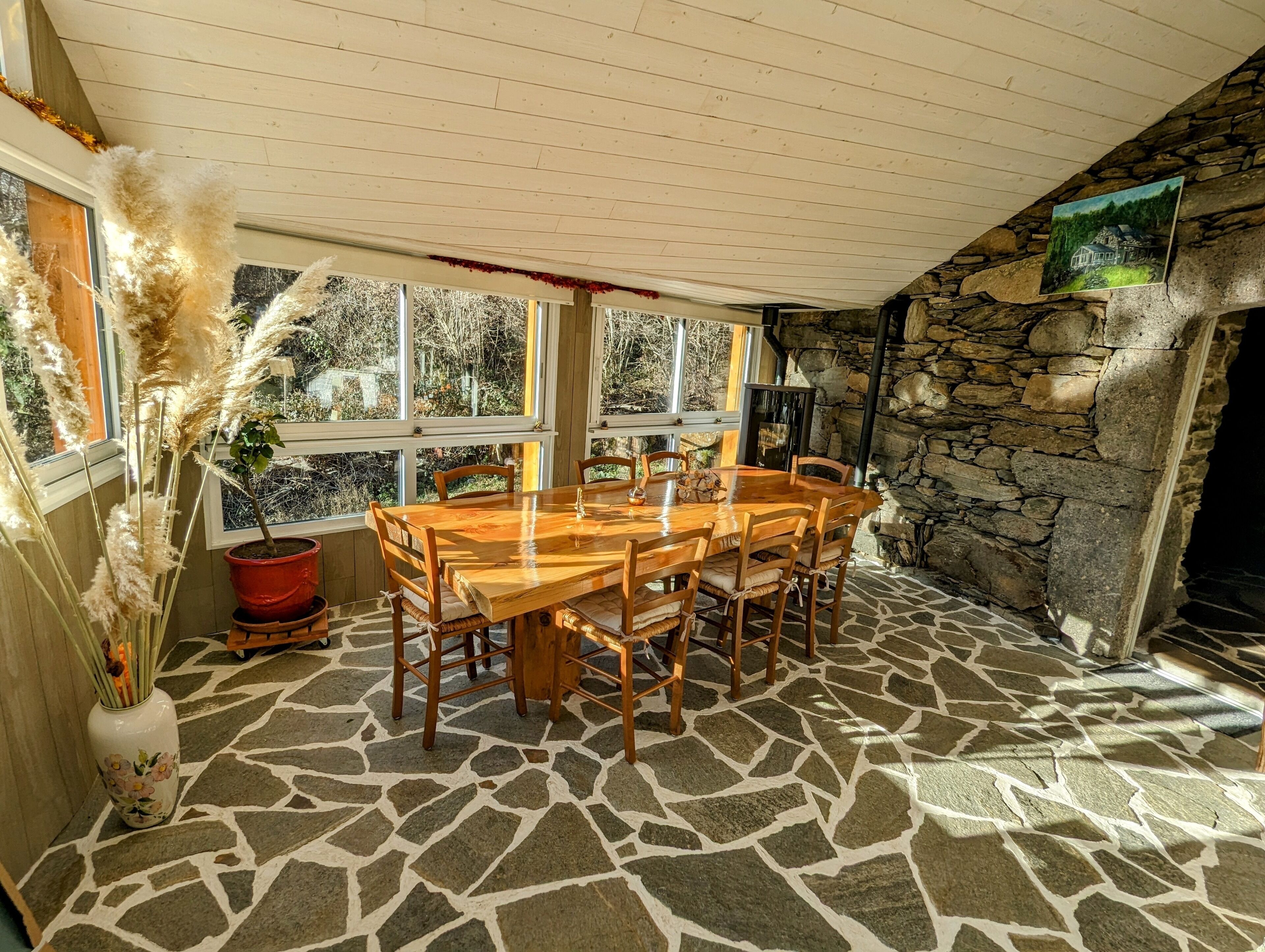 A dining area with a stone floor, wooden table, and chairs.