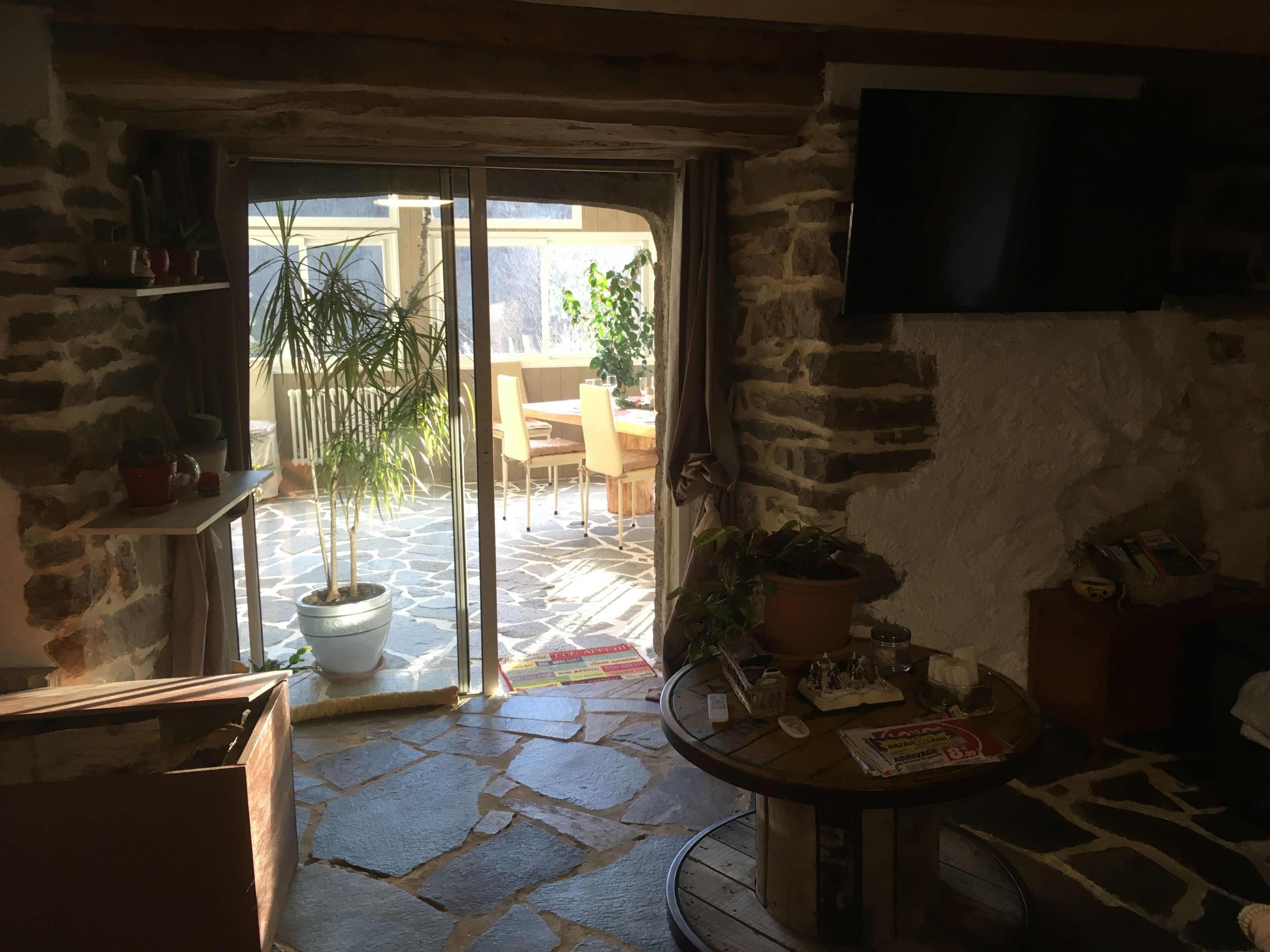 Habitación con piso de piedra y puerta corredera de vidrio que da a un espacio exterior con una mesa y sillas.