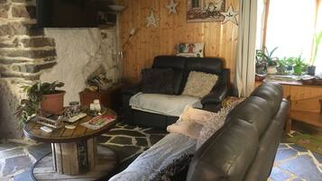 A cozy living room with a fireplace, a leather sofa, a coffee table, and various decorative items.
