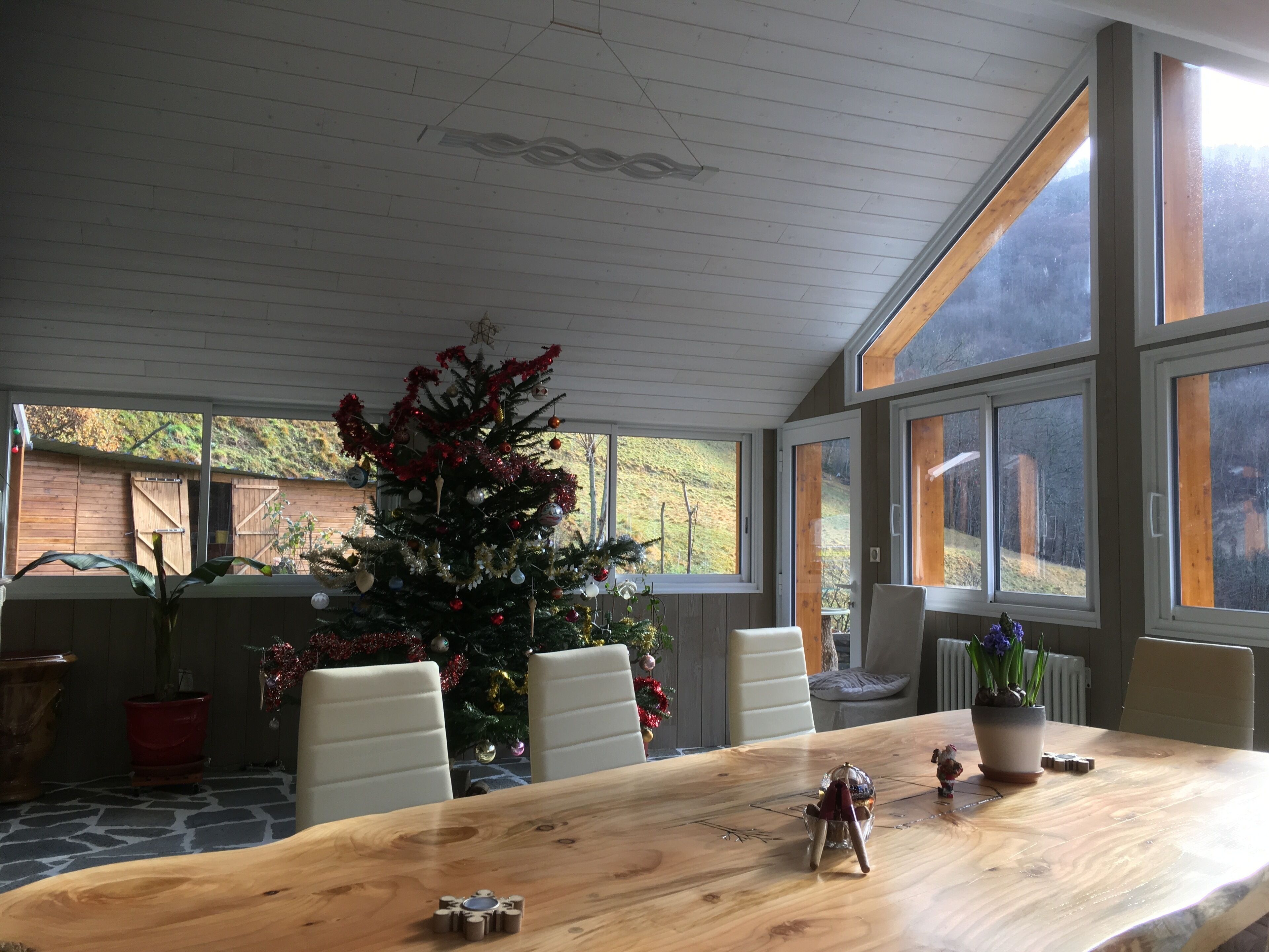 Ein Essbereich mit Holztisch, weißen Stühlen und einem Weihnachtsbaum.