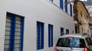 Un edificio blanco con marcos de ventana azules y un coche plateado estacionado.